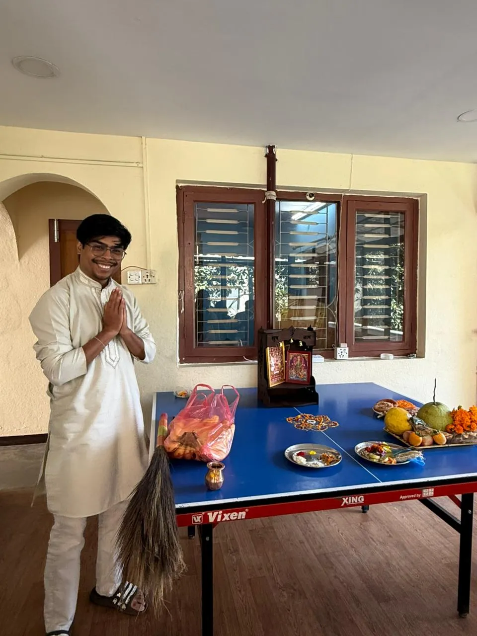 En kollega i traditionell klädsel hälsar namaste bredvid festivalens puja på kontoret
